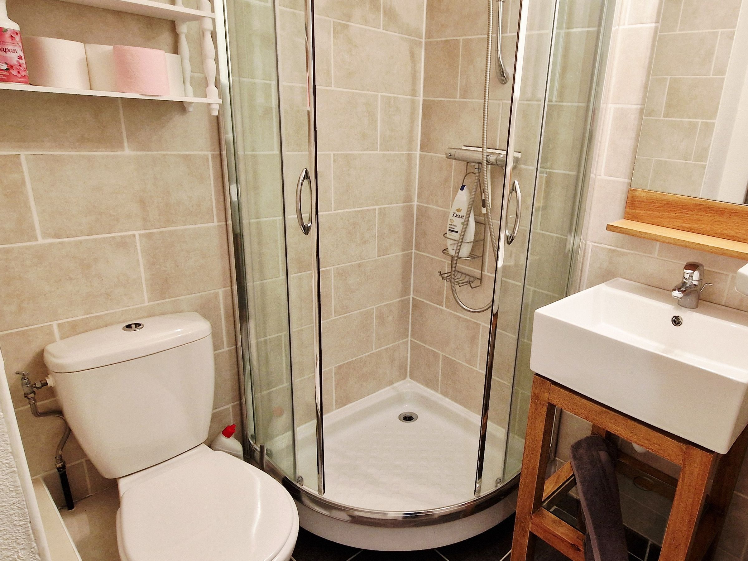 A bathroom with a glass-enclosed shower, a toilet, and a sink.