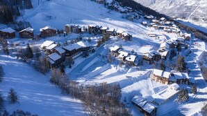 A snow-covered mountain resort with multiple chalet-style buildings, ski slopes, and a clear view of the surrounding mountains. - 3-room apt, 6-8 people, near slopes - La Plagne Montalbert (La Plagne Montalbert)