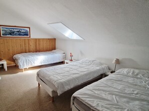 Une chambre avec deux lits, une tête de lit en bois, une petite table, une lampe et un tableau au mur.