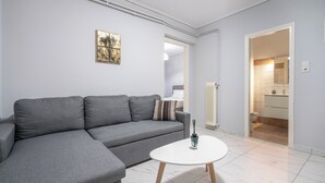 Una sala de estar moderna con un sofá seccional gris, una mesa de centro redonda blanca y un cuadro en la pared.