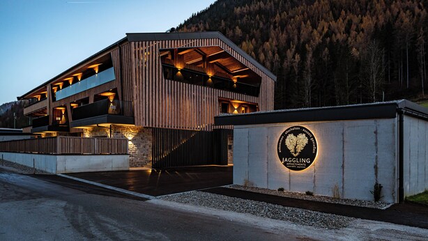 A modern building with a wooden facade and a sign indicating it is a hotel.