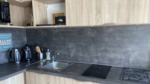 Una cucina moderna con mobili in legno, un piano di lavoro nero, una macchina da caffè, un bollitore e un lavello.