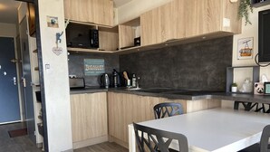 Una cucina compatta con mobili in legno, un forno a microonde integrato e un'area pranzo con tavolo e sedie.