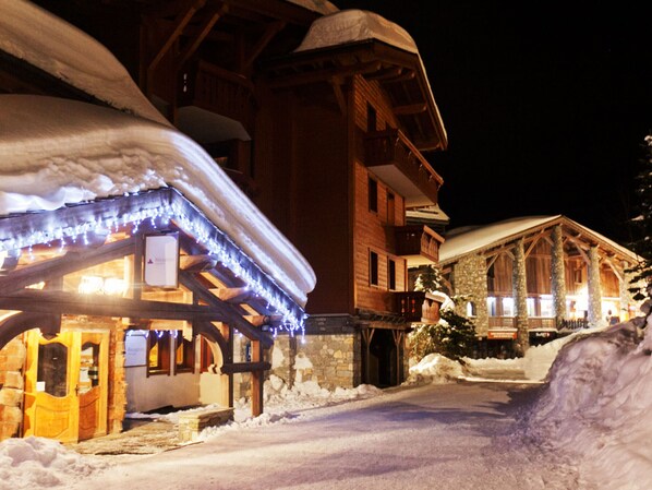 A snow-covered building with a wooden facade and a stone entrance.
