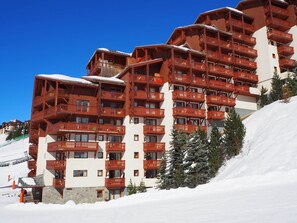 A multi-story hotel with wooden balconies and a snow-covered slope. - Les Menuires - 3 rooms, 6 guests, southwest balcony (Les Menuires)