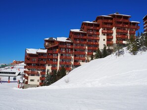 Ein mehrstöckiges Hotel mit Balkonen, gelegen an einem verschneiten Hang.