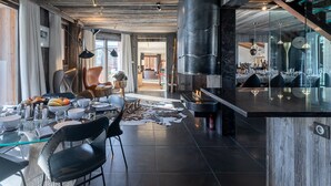Eine moderne Küche mit einer zentralen Kochinsel, einem Essbereich mit Stühlen und einem großen Fenster, das viel Tageslicht hereinlässt.