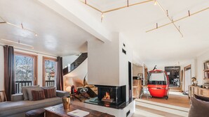 Ein modernes Wohnzimmer mit Kamin, einer Couch, einem Couchtisch und einem roten Fahrzeug im Hintergrund.