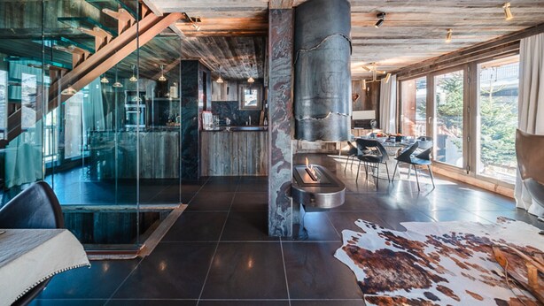 Ein modernes Interieur mit einer Glaswand, einem Kamin und einem Essbereich mit großem Fenster.