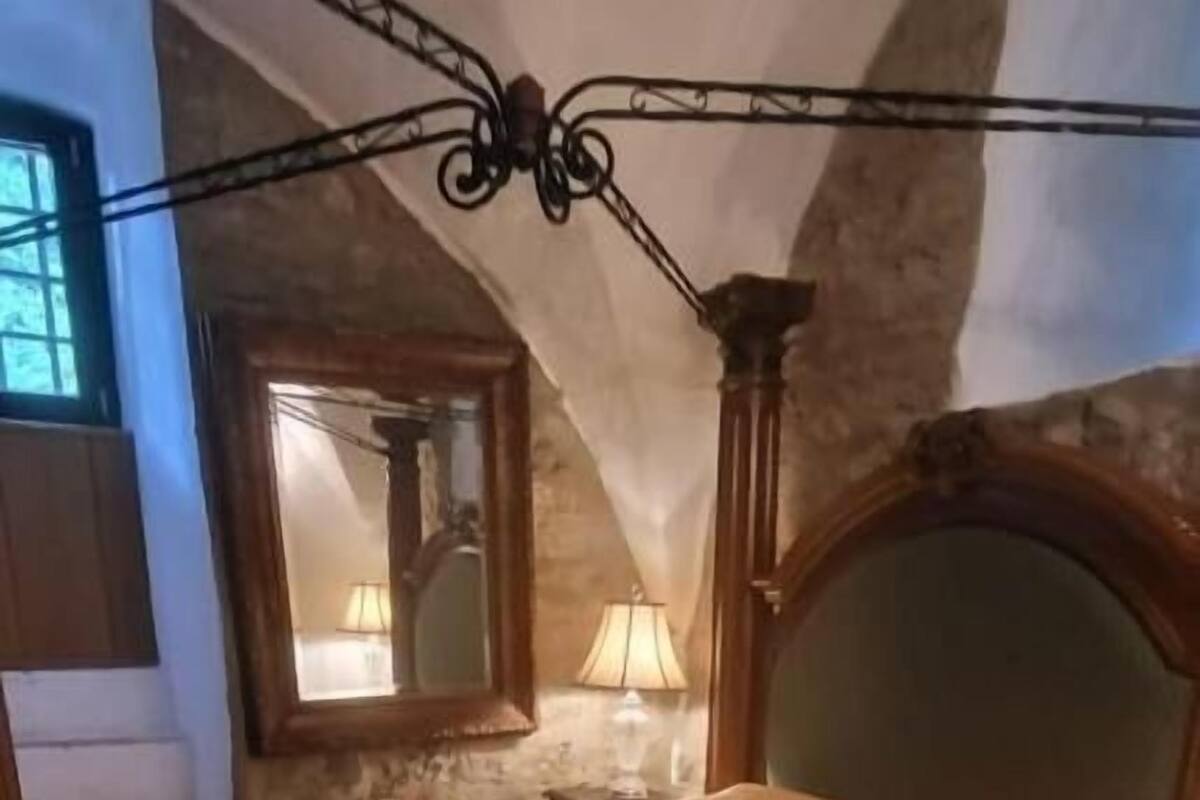 A bedroom with a bed, a nightstand, a lamp, and a window.