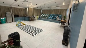 A spacious living area with a sofa set, a play area with a slide, and a kitchen in the background. - The Tranquo Stays (Alibag)