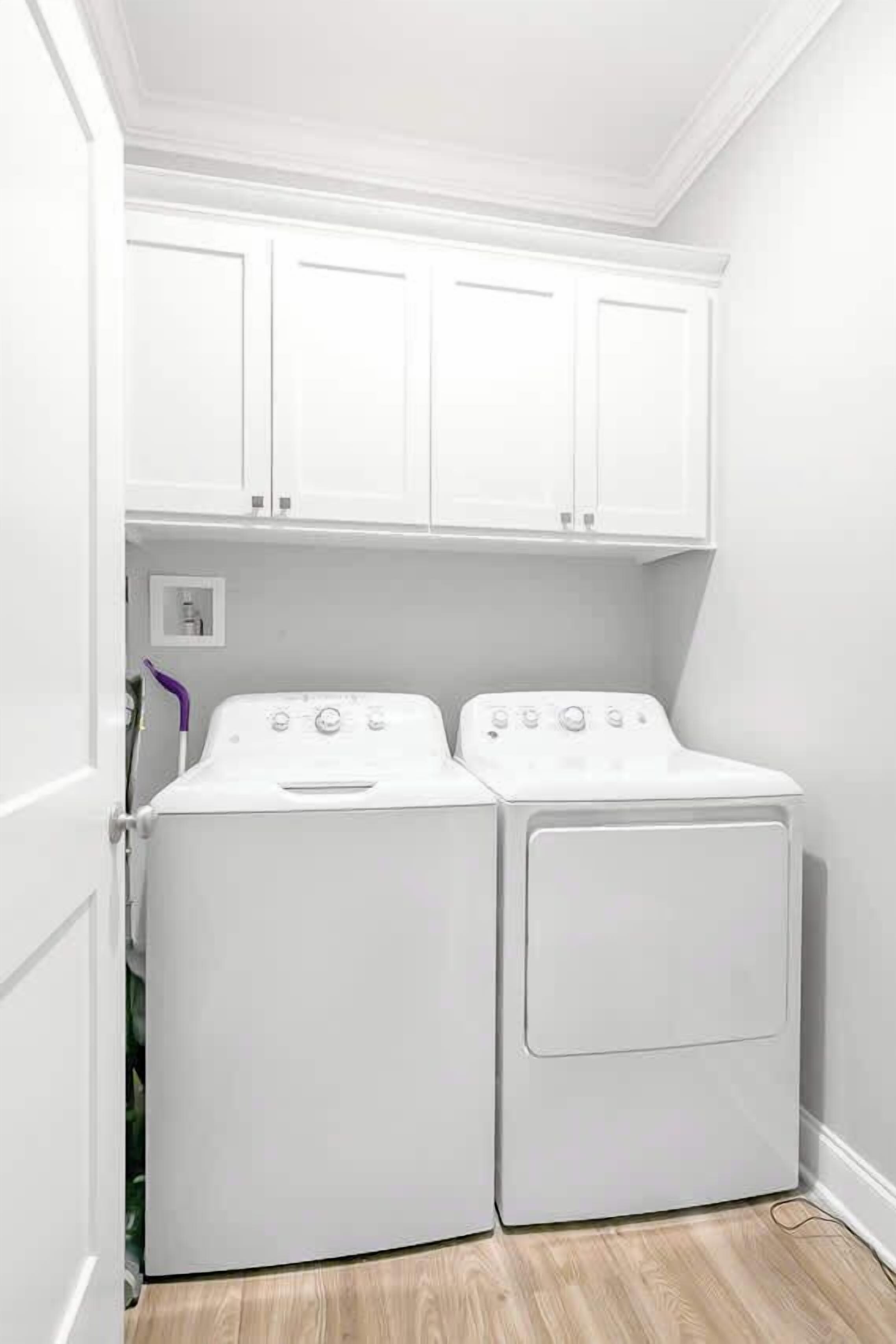 Un cuarto de lavandería con dos lavadoras blancas, una puerta blanca y un interruptor de luz en la pared.