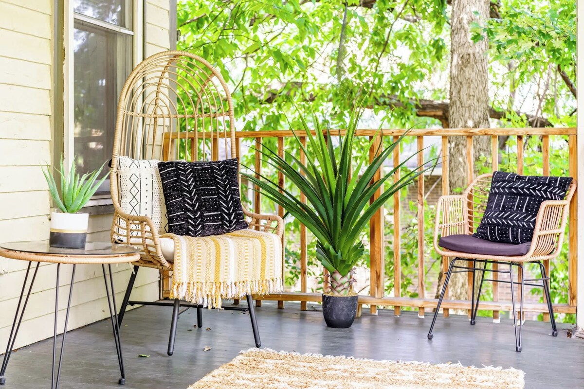 A porch with two wicker chairs, a small table, and a potted plant.
