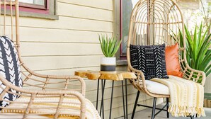 Wicker chairs, a small table, and a potted plant on a porch with a yellow wall and windows. - Jungle House Boutique Lofts – Downtown Columbus & Short North (Columbus)