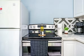 A kitchen with a stove, a refrigerator, and a patterned backsplash. - Jungle House Boutique Lofts – Downtown Columbus & Short North (Columbus)