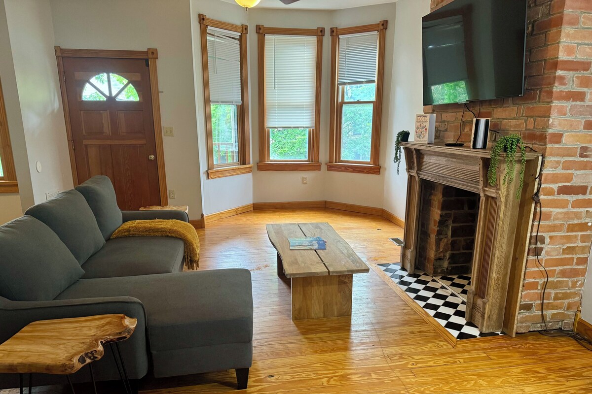 A living room with a gray sofa, wooden coffee table, and a fireplace with a brick wall.