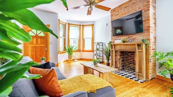 A living room with a fireplace, a sofa, a coffee table, and a TV mounted on the wall.