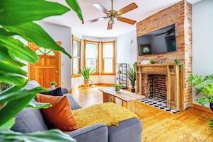 A living room with a fireplace, a sofa, a coffee table, and a TV mounted on the wall.