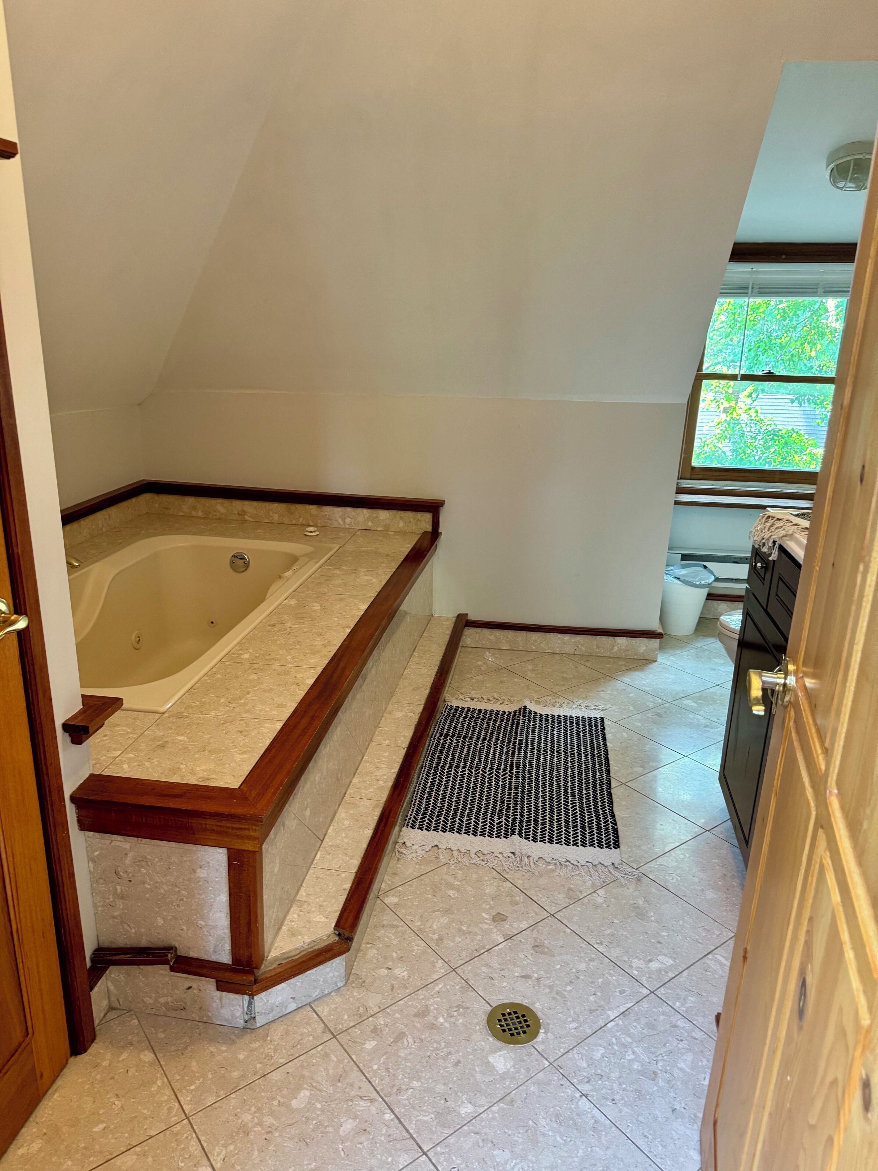 A bathroom with a bathtub, a shower, a window, and a door.