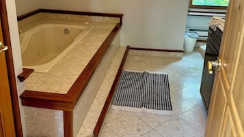 A bathroom with a bathtub, a shower, a window, and a door.