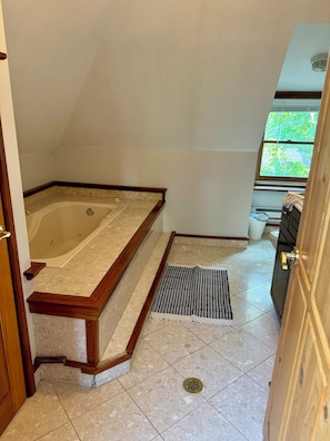 A bathroom with a bathtub, a shower, a window, and a door. - Jungle House Boutique Lofts – Downtown Columbus & Short North (Columbus)