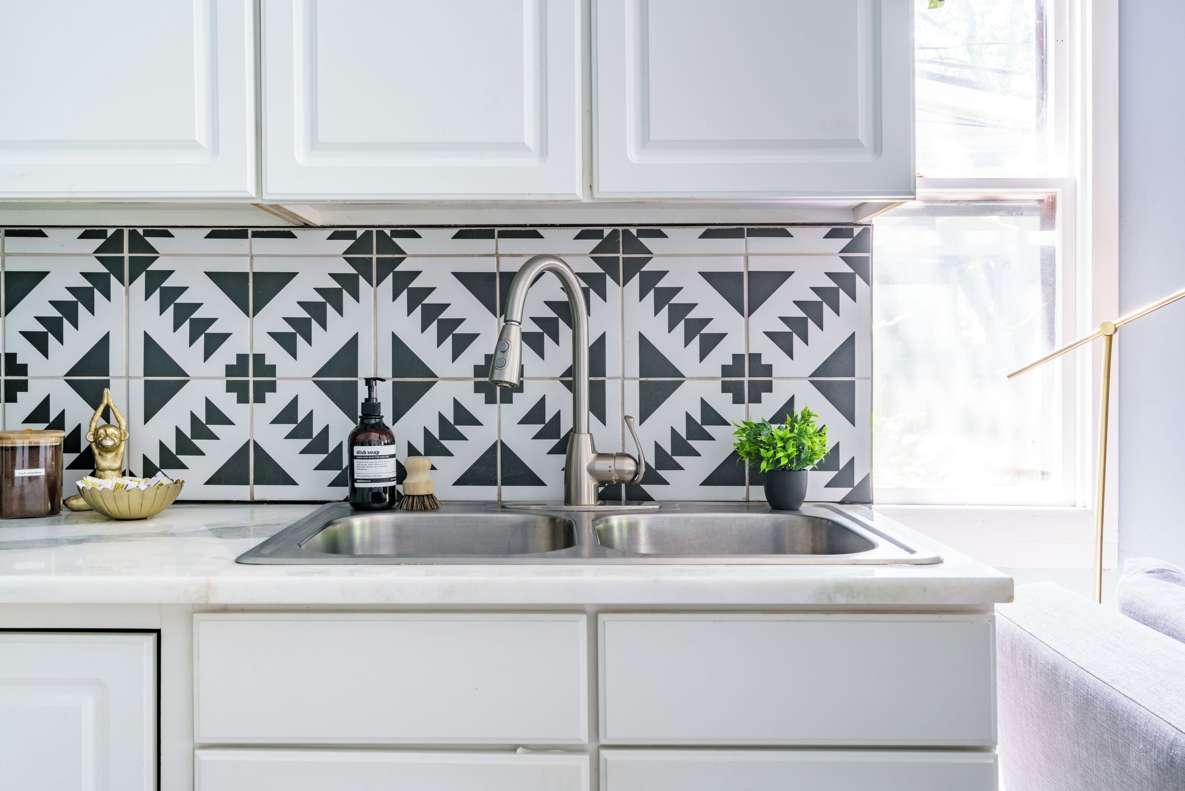 A kitchen with a modern faucet, a sink, and a patterned backsplash.