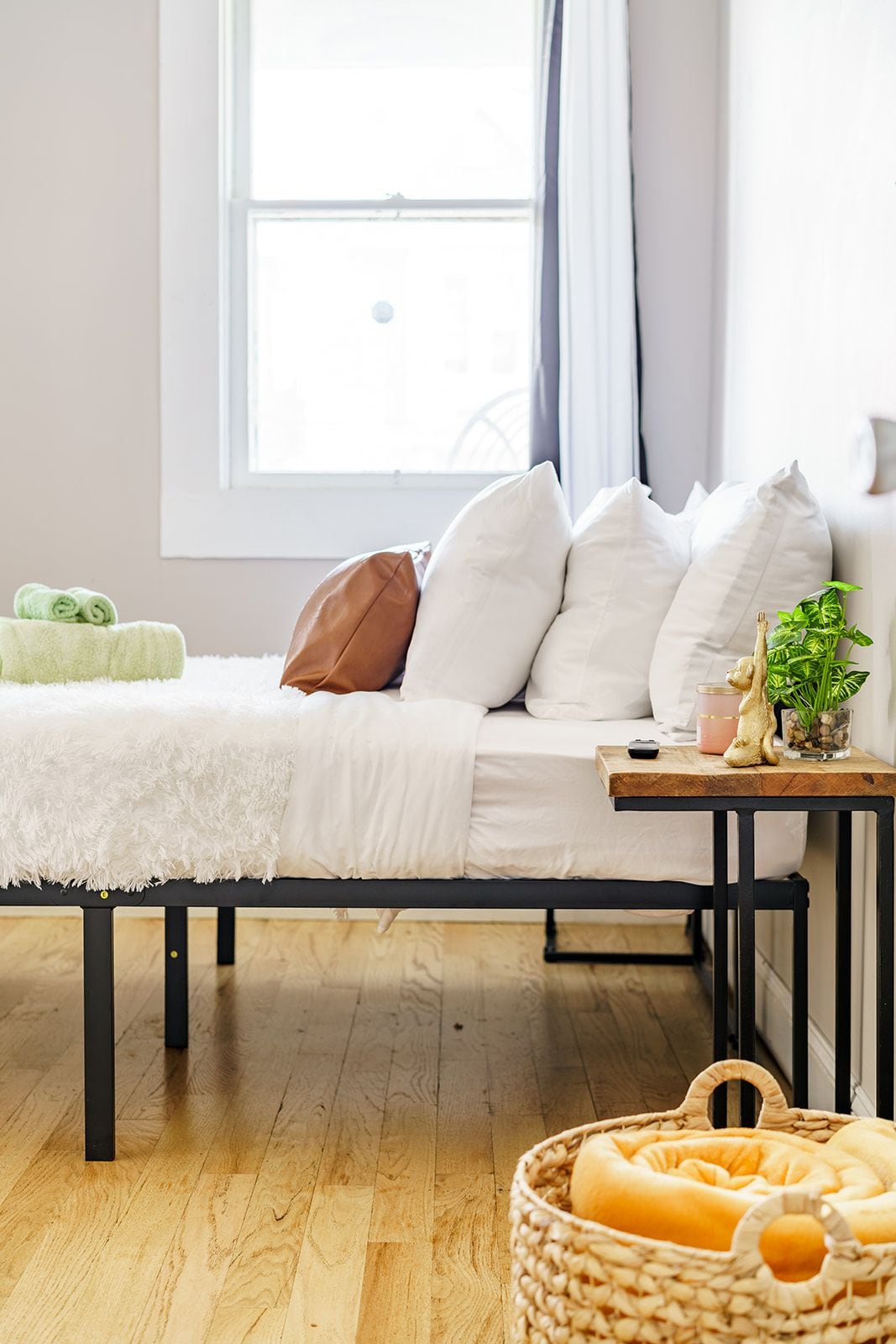 Ein gemütliches Zimmer mit einem Bett, einem kleinen Tisch mit einer Pflanze und einem Korb auf dem Boden.