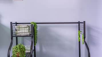 Een kamer met een aan de muur hangend beeld van strandstoelen, een zwarte metalen bank met planten en een witte stopcontact.