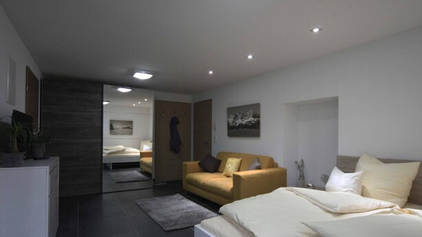 Un dormitorio moderno con una cama, un sofá y un escritorio.