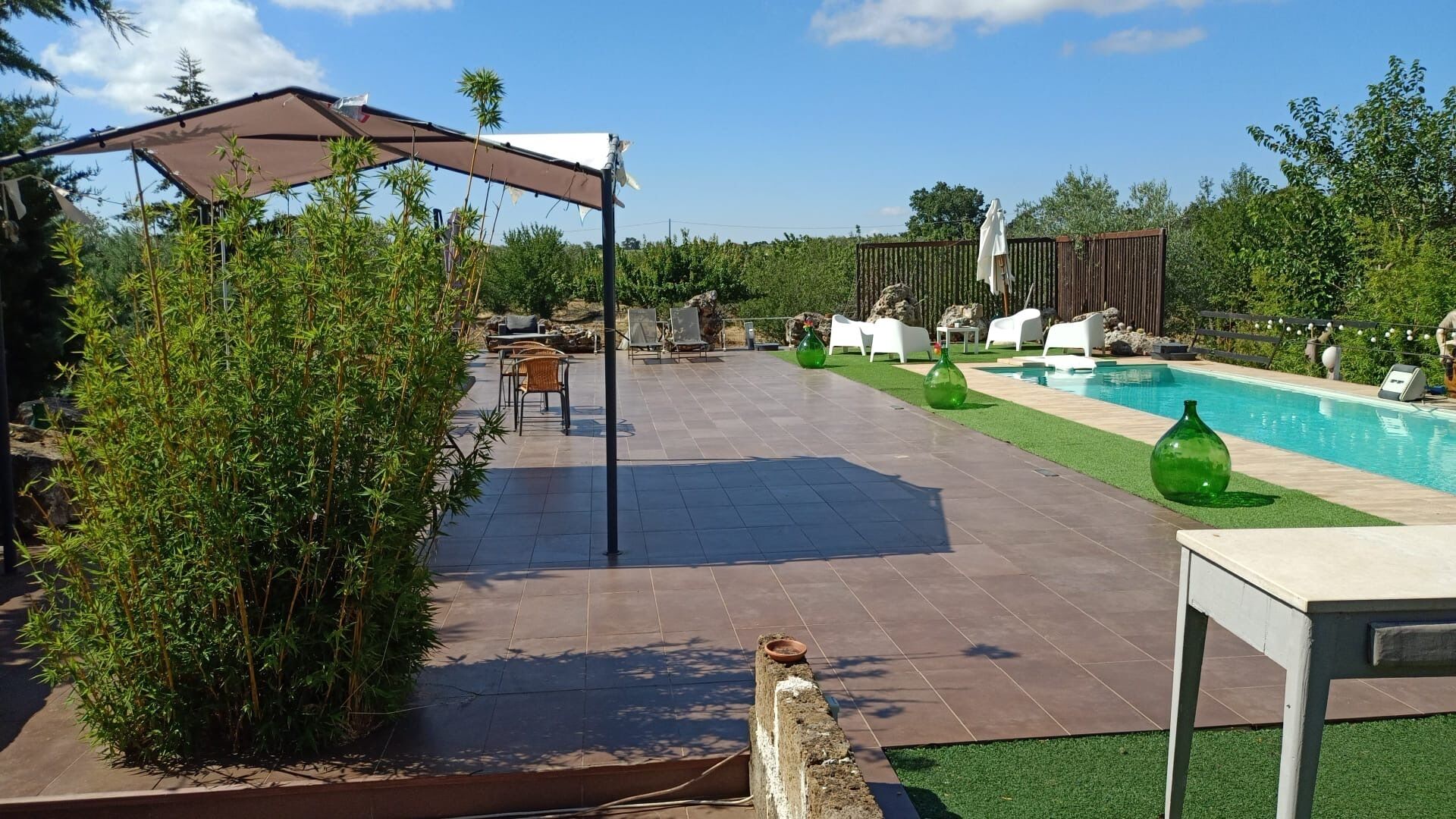 Uma área de pátio com piscina, móveis de exterior e um pergolado.