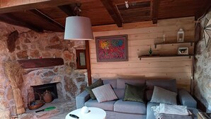 A cozy living room with a stone fireplace, a sofa, a coffee table, and a hanging lamp. - Borgo Incanto (Acquaviva delle Fonti)