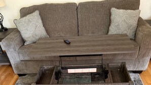 Un salon avec un canapé marron, une table basse en bois et un tapis à motifs.
