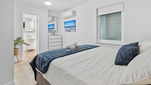A bedroom with a bed, a window, a mirror, and a bathroom visible in the background. - Sea view Retreat - Spot Dolphins (Shoalwater)