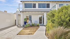A modern two-story house with a covered patio, a small garden, and a clear sky. - The Coastal Haven 1BR (Shoalwater)