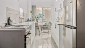 A modern kitchen with a central island, stainless steel appliances, and a view into the dining area. - The Coastal Haven 1BR (Shoalwater)