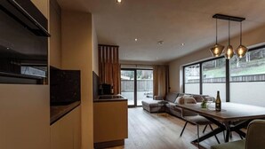 A modern kitchen with a built-in oven, a dining area with a wooden table and chairs, and a large window providing a view of the outdoors.
