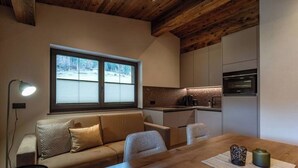 Een gezellige woonkamer met een bank, een eettafel en een keuken op de achtergrond.