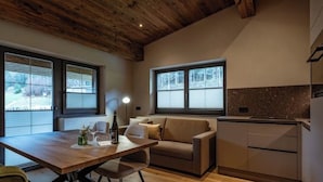 Een moderne keuken met houten balken, een eethoek met tafel en stoelen, en een bank.
