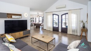 Ein modernes Wohnzimmer mit einem Flachbildfernseher, einem Couchtisch aus Holz und grauen Sofas.