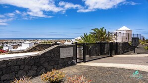 Blick auf die Küste mit einer Steinmauer, einem Tor und einem Schild mit der Aufschrift 'Ocean View Calle Australia 3'.