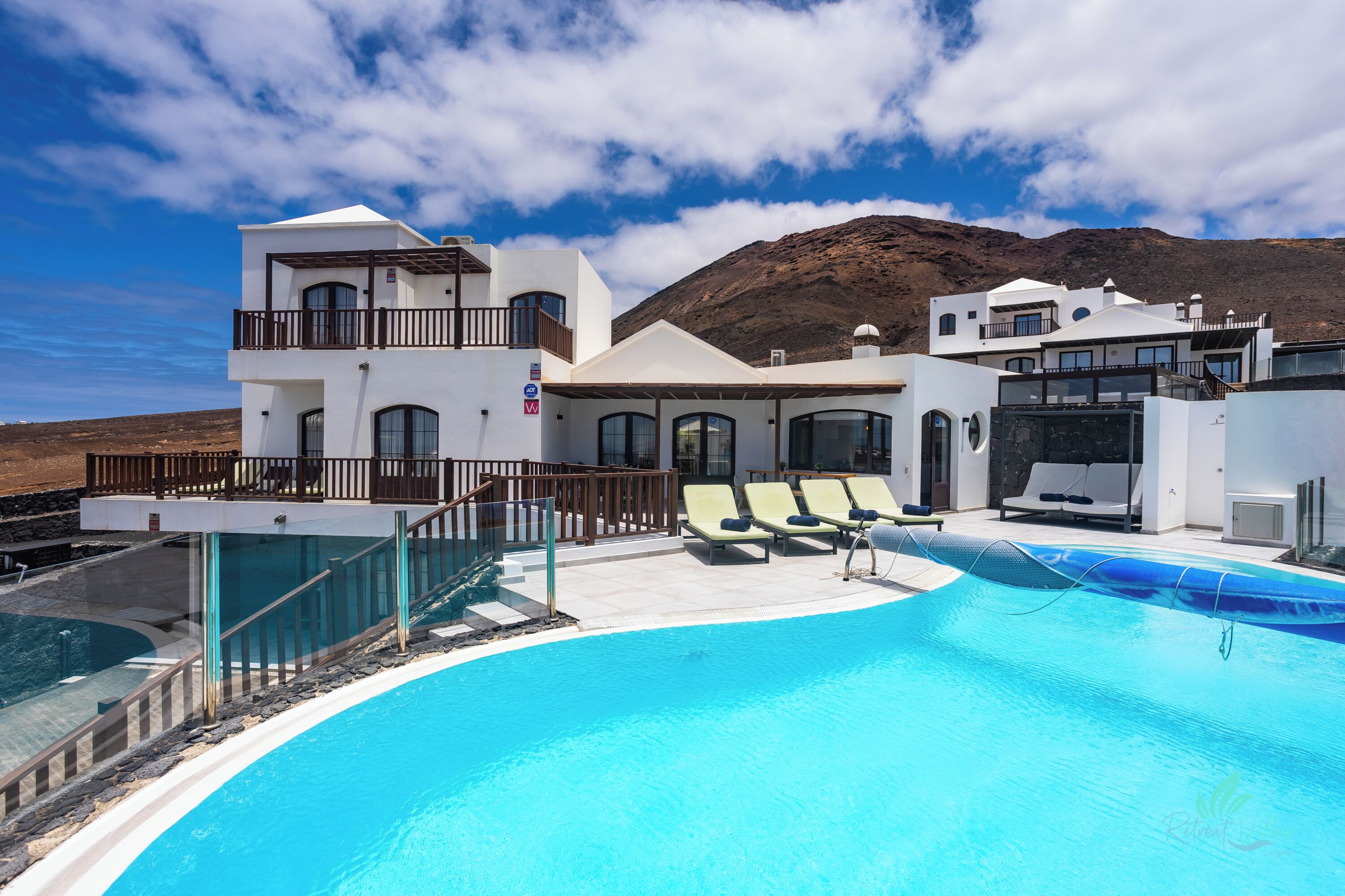 Ein modernes Resort mit Pool, Liegestühlen und Blick auf die Berge.