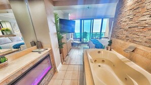 A modern bathroom with a large bathtub, a shower area with a glass enclosure, and a view of the balcony. - Modern Awesome Jacuzzi Romance Condo w 2 bathrooms (Myrtle Beach)