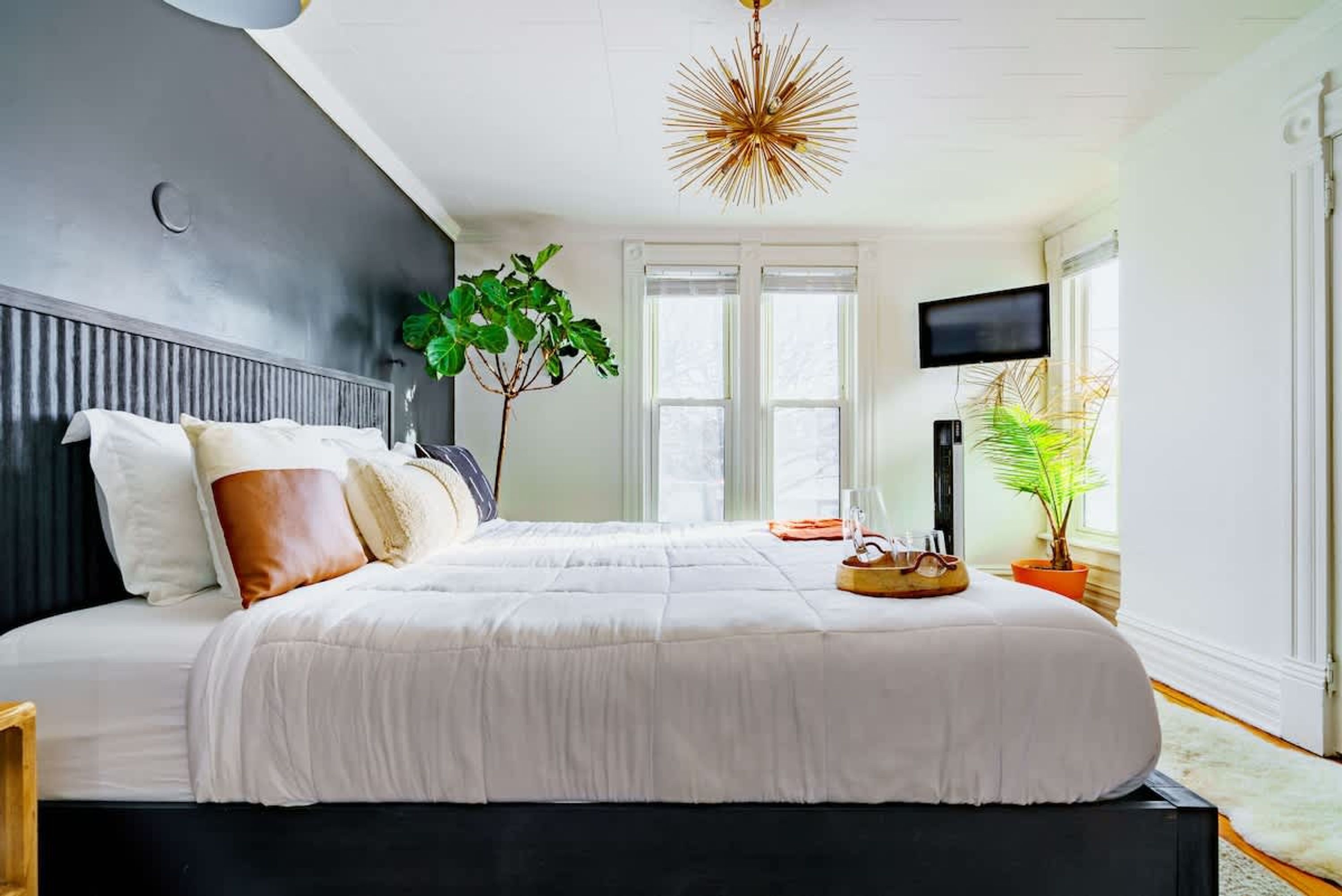 Quarto com cama grande, televisão e luminária de teto singular.