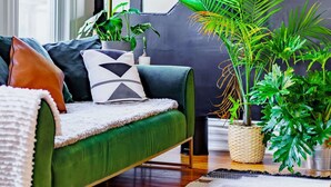A modern living room with a green sofa, decorative pillows, a woven rug, and potted plants. - Short North Convention King Bed Parking Free (Columbus)