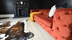 Un moderno salón con un sofá rojo, una chimenea y una alfombra de piel de vaca.