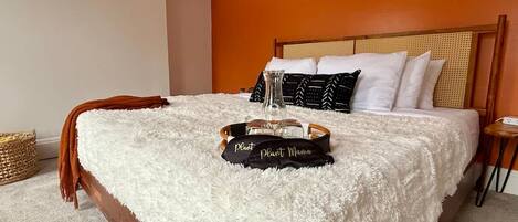 A bedroom with a large bed, a headboard with a woven design, and a bedside table with a lamp.