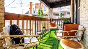 An outdoor balcony with wicker furniture, a small table, and a potted plant. - Prime Location Top Rated Clean Parking Free (Columbus)