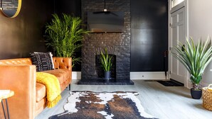 Una sala moderna con un sofá de cuero, una chimenea negra y una planta grande.