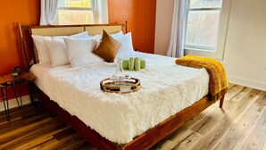 Una cama bien hecha con ropa blanca, cabecero marrón y suelo de madera.