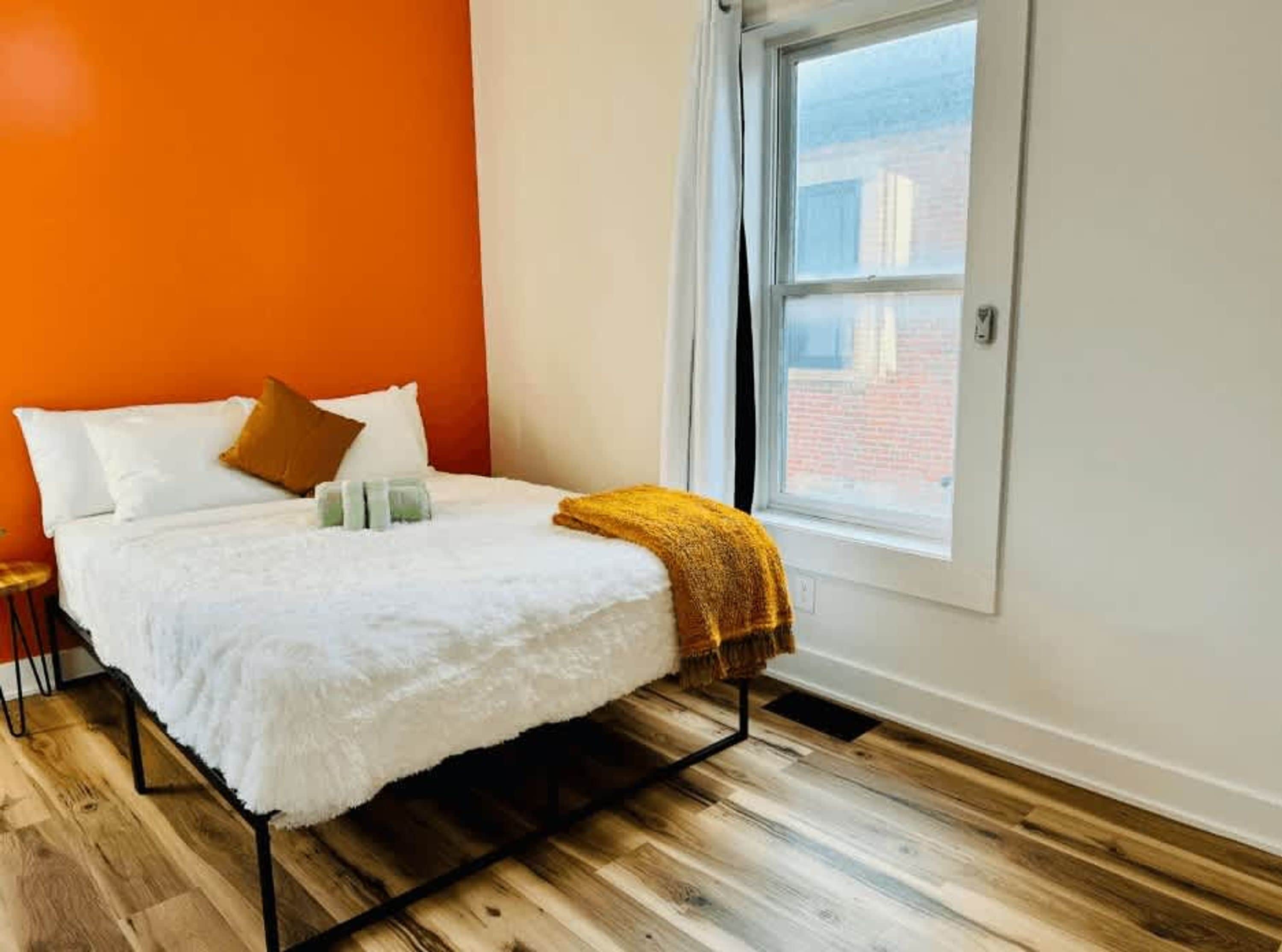 A bedroom with a bed, pillows, a blanket, and a window.